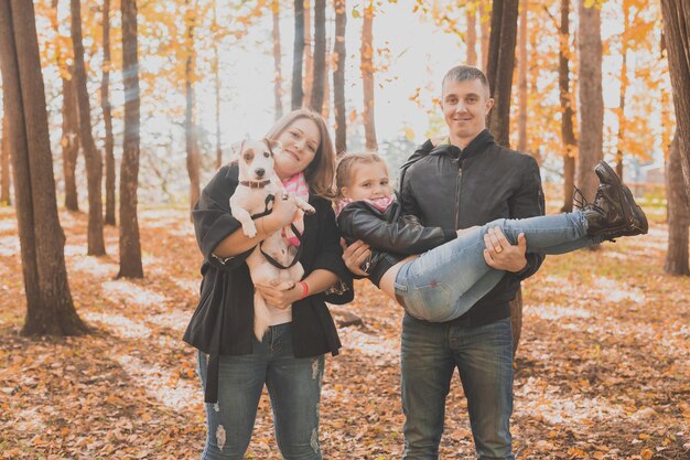 La famille passe du temps dans le parc d'automne avec un chien. Père, mère et fille et chien jack russell terrier s'amusant à l'automne