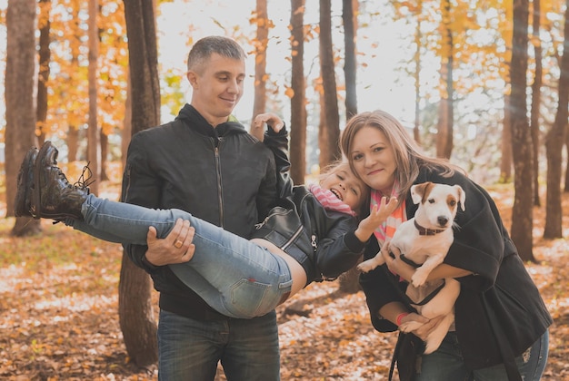 La famille passe du temps dans le parc d'automne avec un chien père mère et fille et chien jack russell terrier