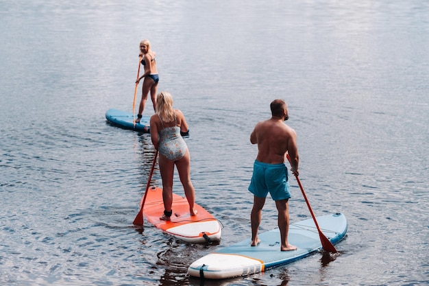 La famille passe du temps ensemble à nager sur des planches sup sur le lac