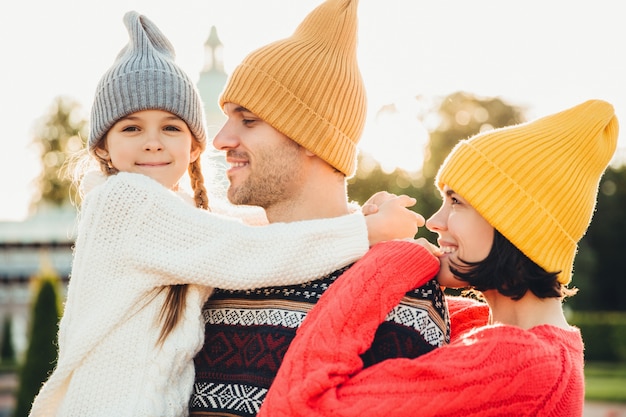 La famille passe des moments inoubliables ensemble, s’embrasse, porte des chapeaux tricotés à la mode