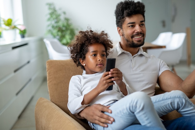 La famille, la paternité aime le concept de personnes. Heureux père et fille regardant la télévision à la maison