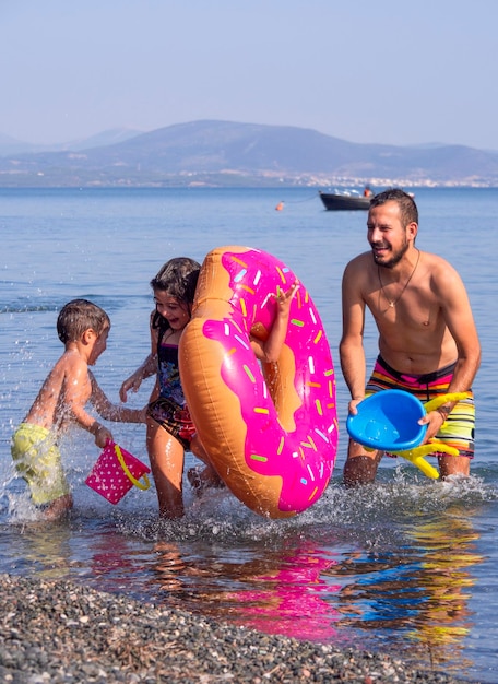 Famille père fille et fils jouent et versent de l'eau sur la plage sur une île grecque un jour d'été