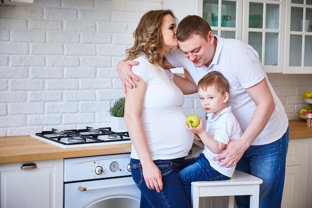 Famille avec un petit enfant et une jeune femme enceinte dans la cuisine.