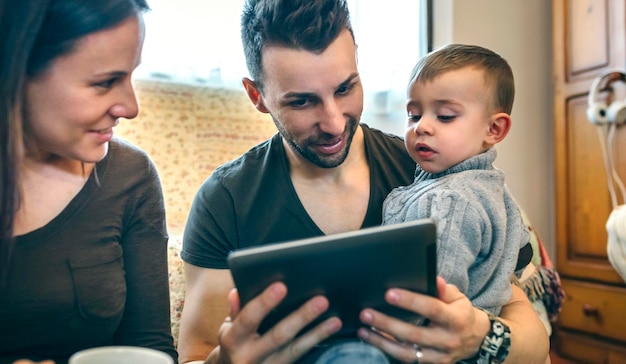 Famille avec petit enfant et mère enceinte regardant la tablette