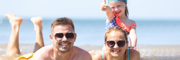 Famille avec petite fille allongée dans la mer