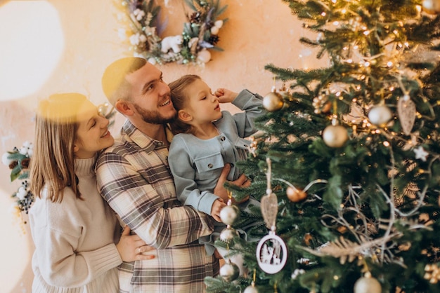 Famille avec petite fille ensemble près de l'arbre de Noël