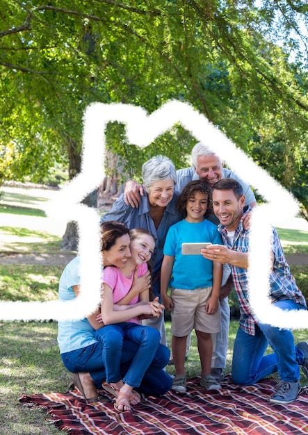 Famille sur plusieurs générations prenant un selfie en plein air contre le contour de la maison en arrière-plan