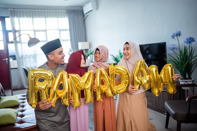 Famille portant des vêtements traditionnels musulmans tenant un texte du ramadan