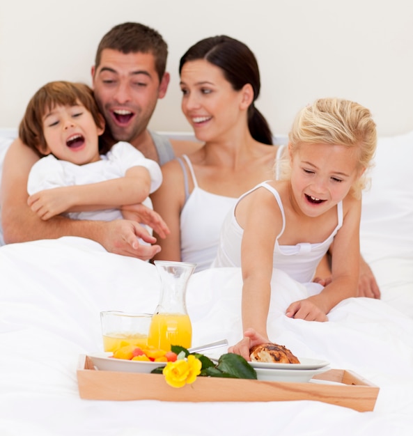 Famille prenant son petit déjeuner au lit le matin