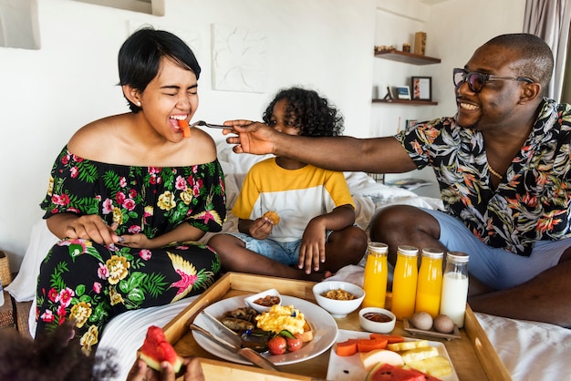 Famille prenant son petit déjeuner au lit