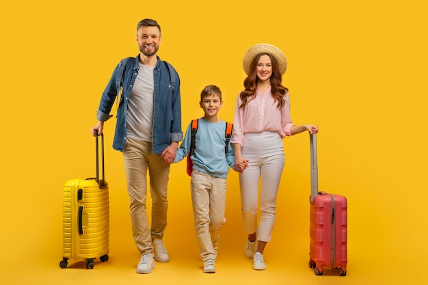 Famille prête pour les vacances avec des bagages sur fond jaune