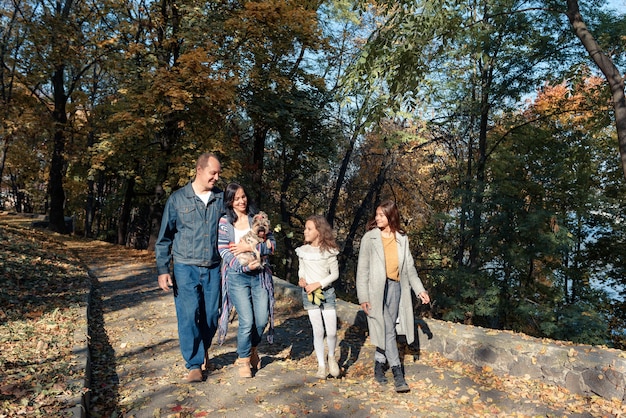 Photo famille promenades dans le parc avec un petit chien par temps ensoleillé