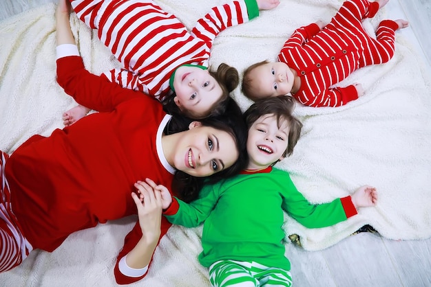 Une famille en pyjama rayé se repose à la maison De petits enfants déguisés en elfes sont allongés sur le canapé Famille heureuse