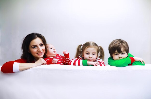 Une famille en pyjama rayé se repose à la maison. De petits enfants déguisés en elfes sont allongés sur le canapé. Happy familywith bannière.