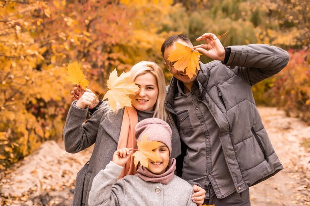 Une famille de quatre personnes profitant de feuilles d'or dans le parc d'automne