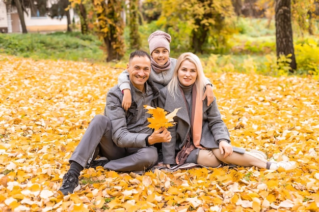 Une famille de quatre personnes profitant de feuilles d'or dans le parc d'automne