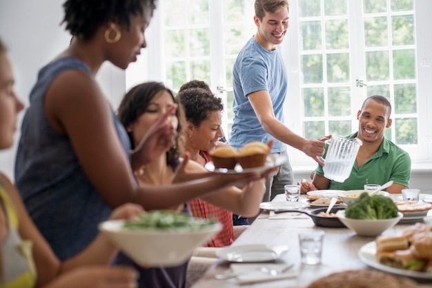 Une famille rassemblant hommes femmes et enfants autour d'une table à manger partageant un repas