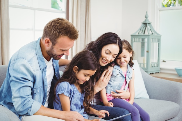 Famille à la recherche dans une tablette numérique assis sur un canapé