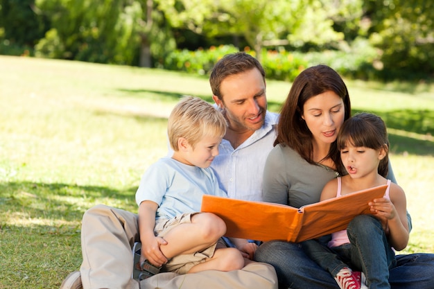 Famille regardant leur album photo dans le parc