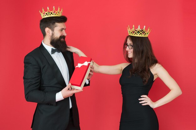 Famille royale Couple amoureux famille royale Société d'élite Événement officiel du roi et de la reine Cadeau royal Reine de son cœur Homme barbu roi en smoking couronne dorée donnant une boîte-cadeau à une femme élégante robe