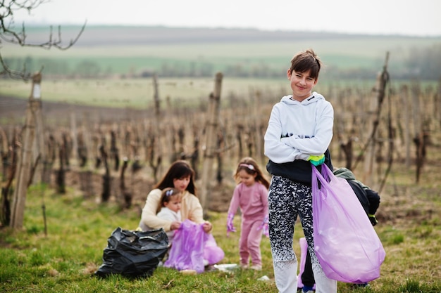 Famille avec sac poubelle ramassant les ordures pendant le nettoyage dans les vignes Conservation de l'environnement et recyclage écologique