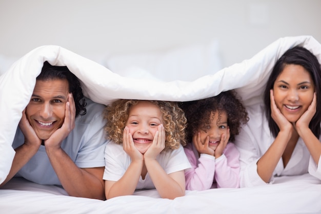 Famille se cachant sous la couverture