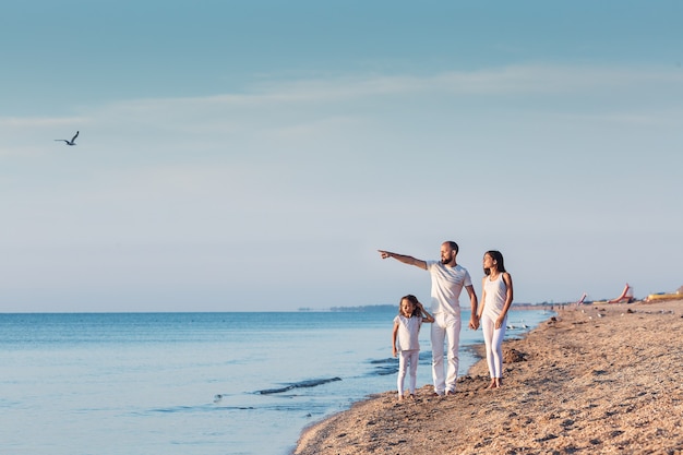 La famille se promène sur la plage à l'aube.