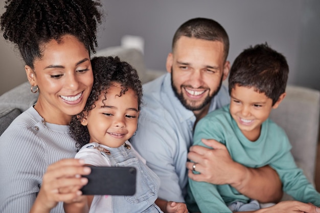 Famille selfie live streaming téléphone et sourire sur Internet avec la technologie heureuse pour l'application mobile et enregistrer une vidéo pour le Web sur le canapé dans le salon Latino mère et père prennent des photos avec les enfants