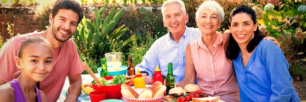 Famille souriant à la caméra tout en prenant un repas à l'extérieur