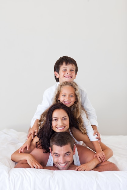 Famille souriante allongée sur leur lit