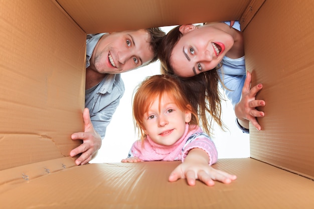 La famille souriante dans une boîte en carton prête pour le déménagement