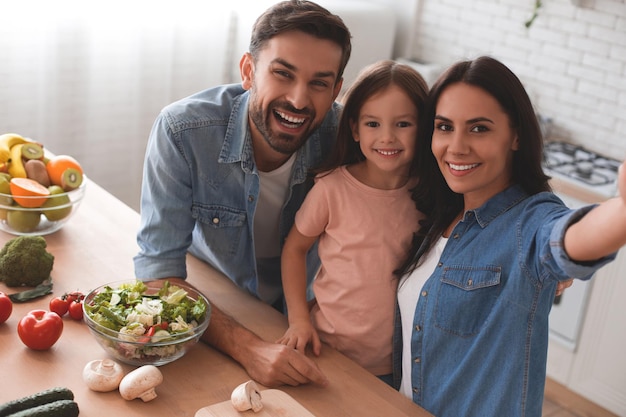 Famille souriante debout sur la cuisine ensemble