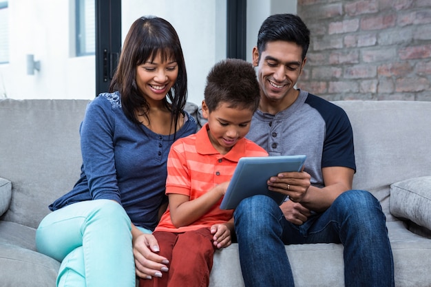 Famille souriante avec tablette sur le canapé