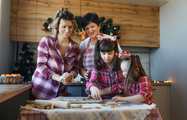 Une famille sympathique dans la cuisine prépare des biscuits à partir de la pâte la veille de Noël.