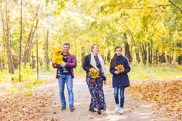 Famille sympathique marchant dans le parc à l'automne ensemble