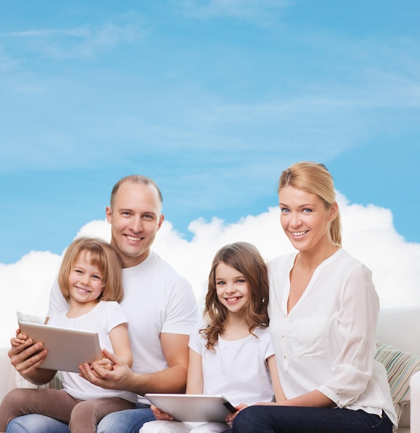 famille, technologie et personnes - mère souriante, père et petites filles avec des ordinateurs tablettes sur ciel bleu et fond de nuage blanc