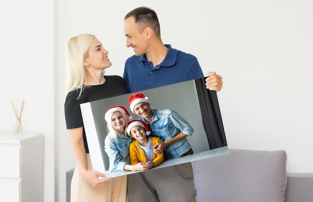 famille tenant une toile photo avec une image de noël.