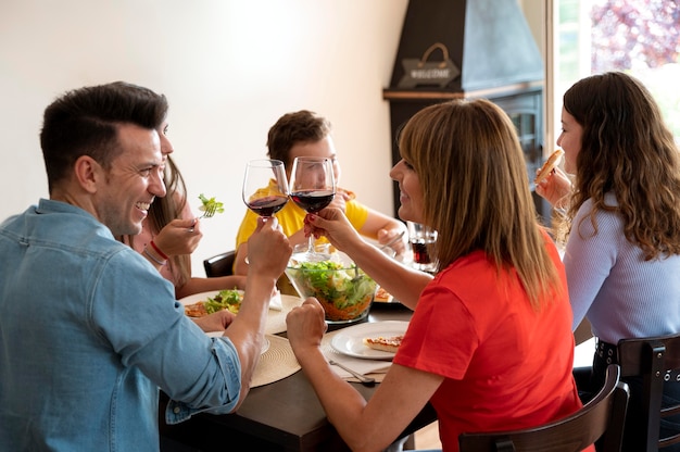 Photo famille en train de dîner ensemble et griller avec des verres à vin