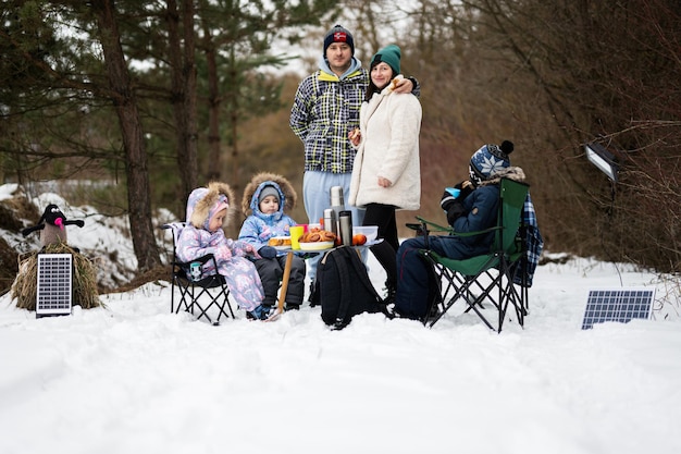 Famille avec trois enfants dans la forêt d'hiver passant du temps ensemble sur un pique-nique