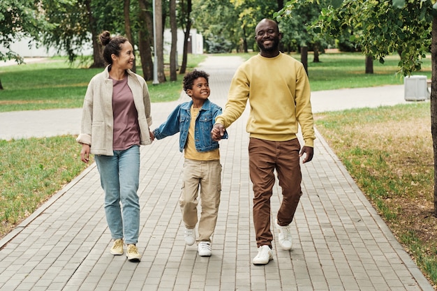 Famille de trois personnes marchant dans le parc