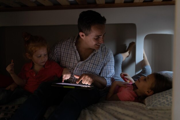 Photo famille utilisant une tablette numérique sur le lit dans la chambre à coucher à la maison