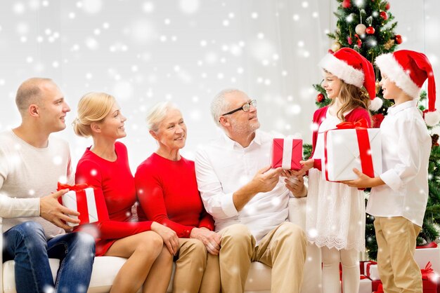 famille, vacances, génération, noël et concept de personnes - famille souriante avec des coffrets cadeaux assis sur un canapé à la maison