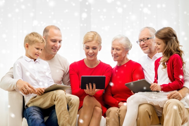 famille, vacances, noël, concept de technologie et de personnes - famille souriante avec des ordinateurs tablettes assis sur un canapé à la maison