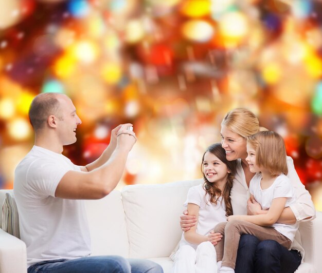 famille, vacances, technologie et personnes - mère souriante, père et petites filles avec caméra sur fond de feux rouges