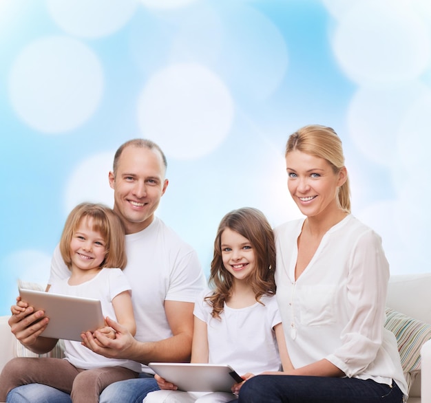 famille, vacances, technologie et personnes - mère souriante, père et petites filles avec des ordinateurs tablettes sur fond de lumières bleues