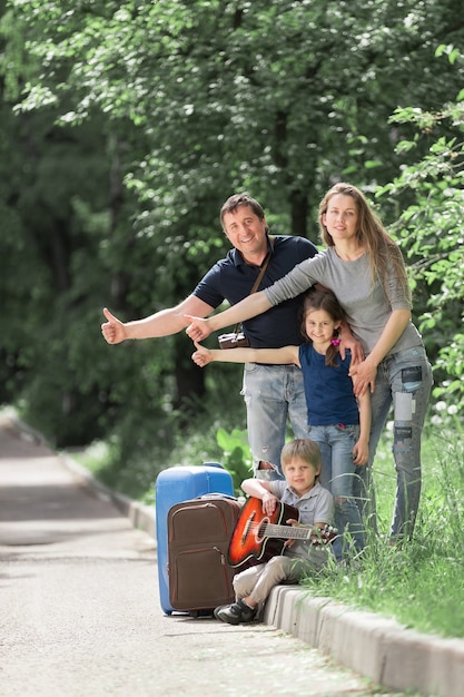 Famille avec valises votant sur la route.