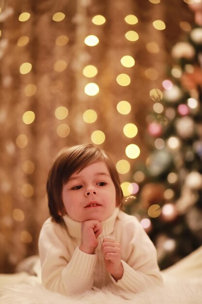 Famille la veille de Noël à la cheminée. Enfants ouvrant des cadeaux de Noël. Enfants sous l'arbre de Noël avec des coffrets cadeaux. Salon décoré avec cheminée traditionnelle. Soirée d'hiver chaleureuse et confortable à la maison.