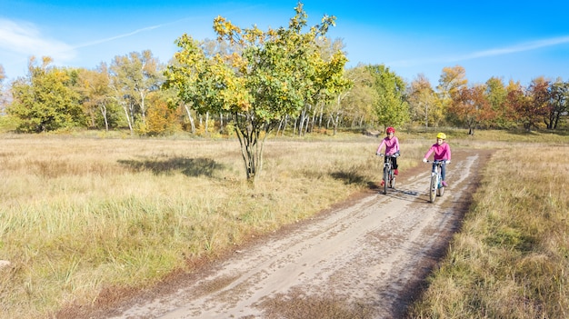 Famille à vélo automne vélo à l'extérieur, mère active et enfant à vélo, vue aérienne de famille heureuse avec enfant dans le parc d'automne par le haut, sport et concept de remise en forme