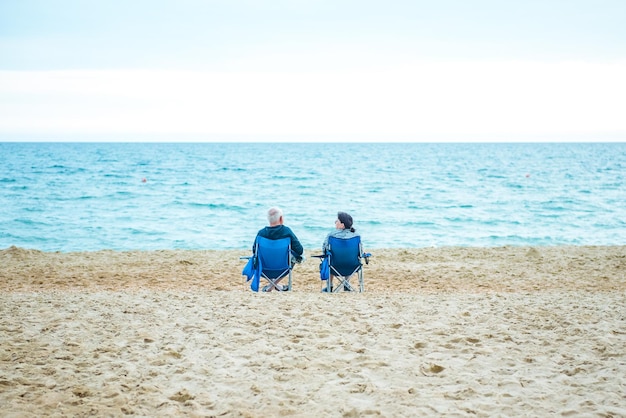 famille vieillesse voyage tourisme heureux couple de personnes âgées assis sur des chaises longues sur la plage d'été