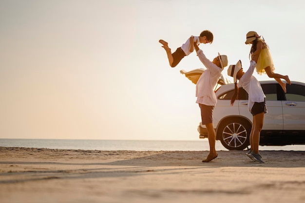 Famille, voyage, plage, détente, style de vie, concept de vacances. Famille qui aime un pique-nique. Parents exerçant son fils et sa fille à la plage au coucher du soleil en vacances.